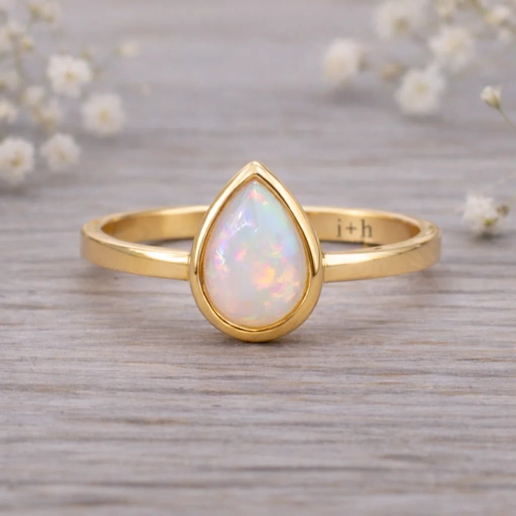 gold ring with tear drop shaped natural opal on a wooden surface