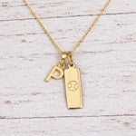 Gold Initial P Pendant and Cancer Zodiac Pendant Necklace on a fine gold chain against a light wooden background