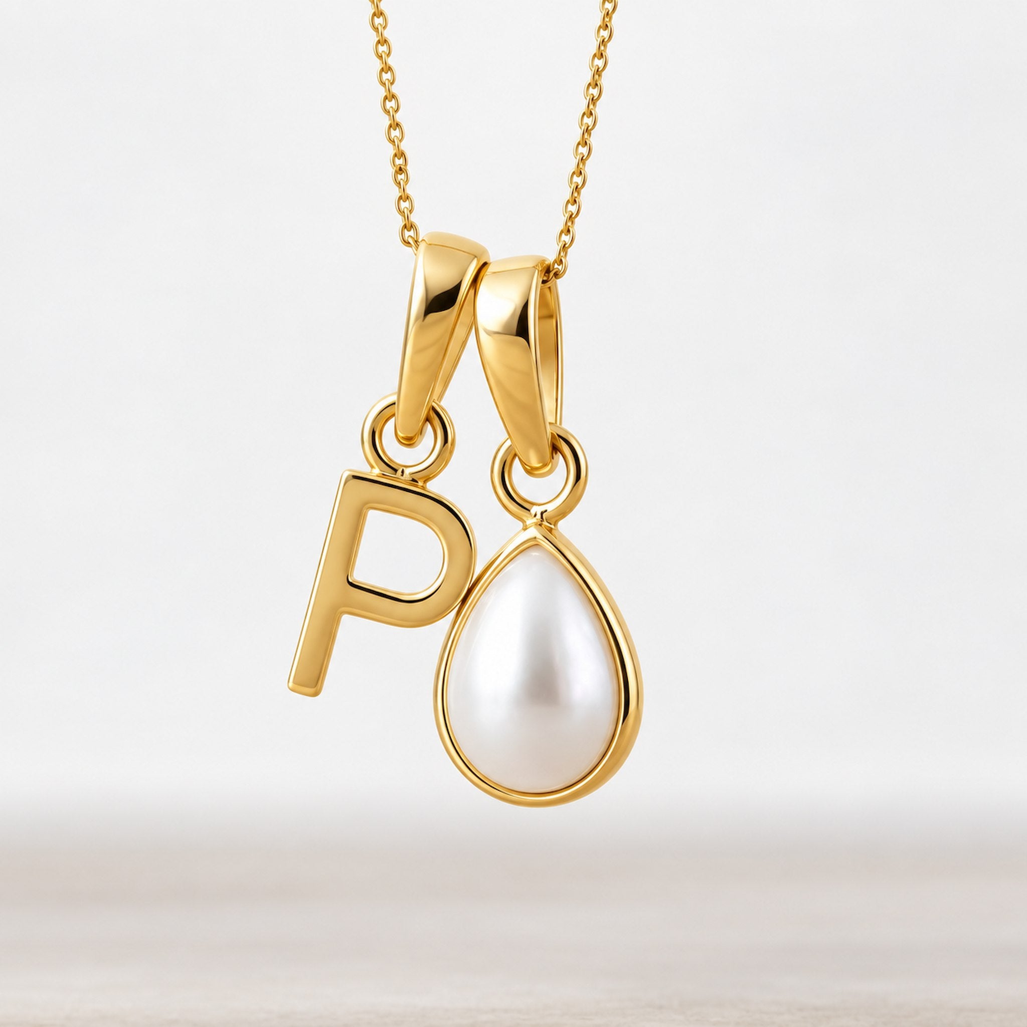 Gold June birthstone necklace with a pear-shaped natural mother of pearl pendant and letter 'P' charm.