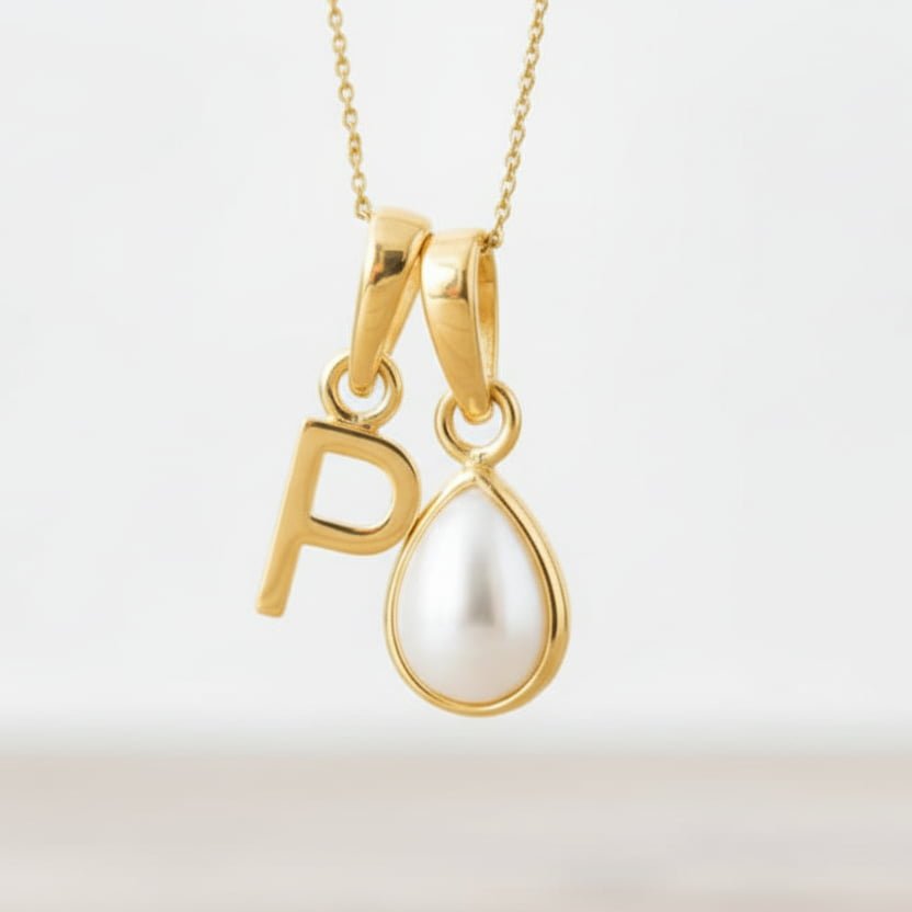 Gold necklace with a 'P' pendant and teardrop-shaped pearl on a light background