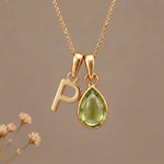 Gold Initial P Pendant and August birthstone Natural Peridot Necklace against a warm background
