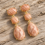 Gold peach sandstone drop earrings on wooden background