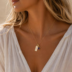 Gold Necklace with teardrop February Birthstone Natural Amethyst pendant and a rectangle pendant wth Pisces line glyph on person wearing a white shirt.