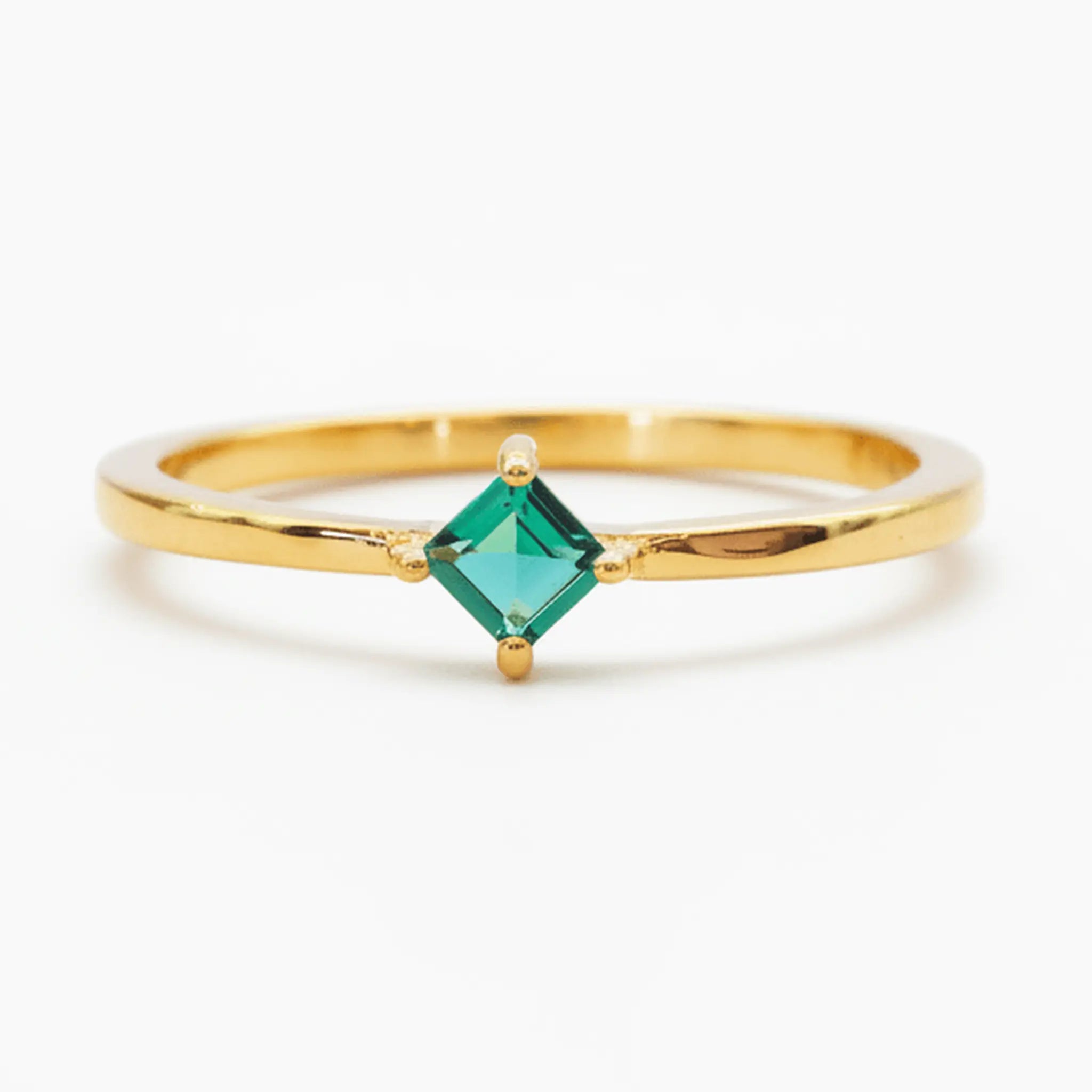 Gold-plated ring with a princess-cut emerald-green cubic zirconia on a white background
