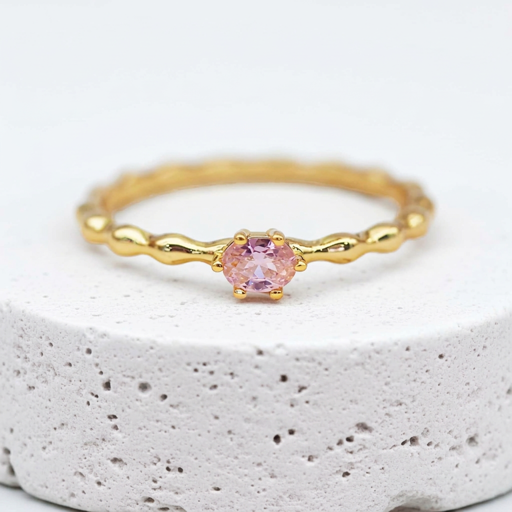 Dainty gold rose quartz ring with a faceted pink stone on textured stone