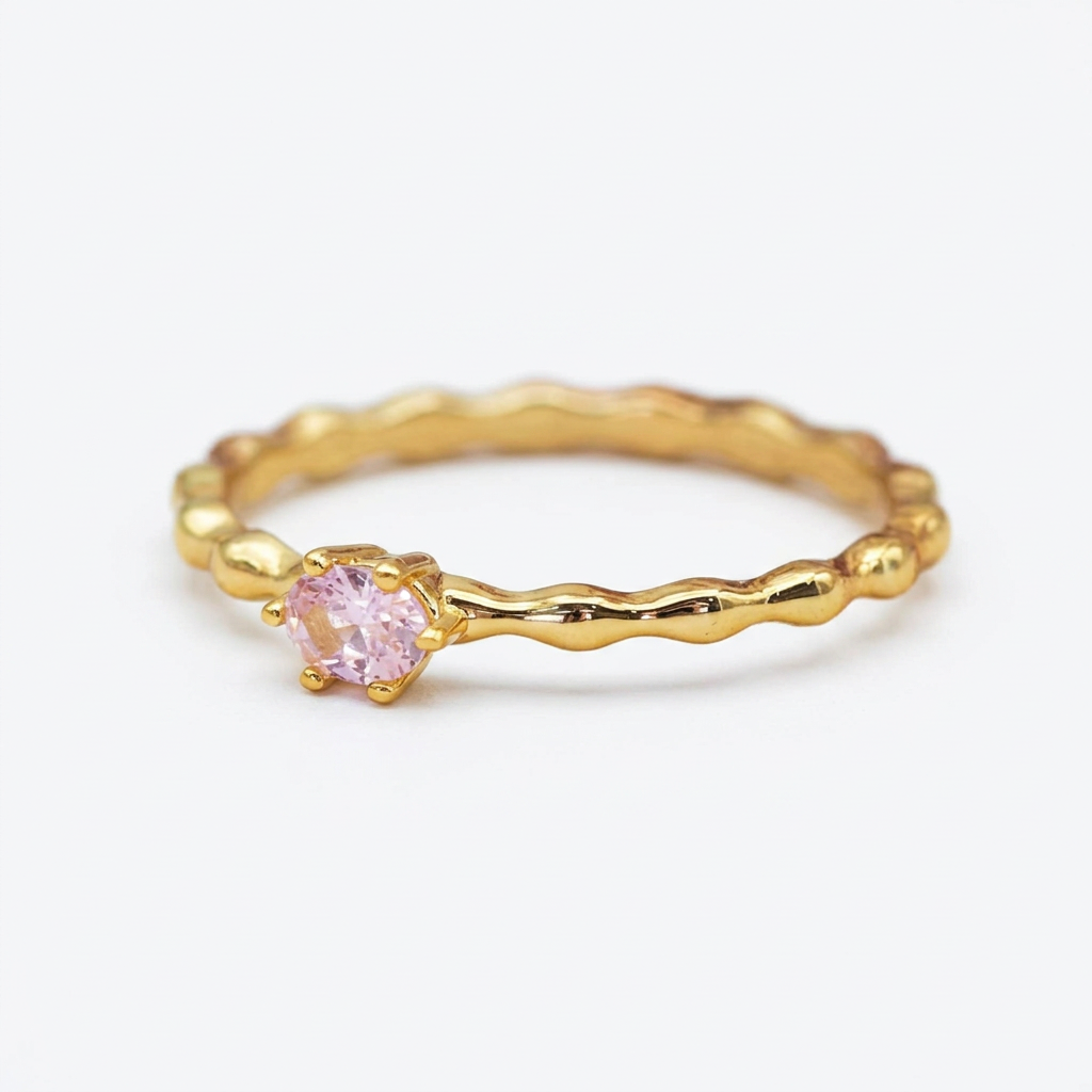 Gold rose quartz ring on white stone with flowers behind