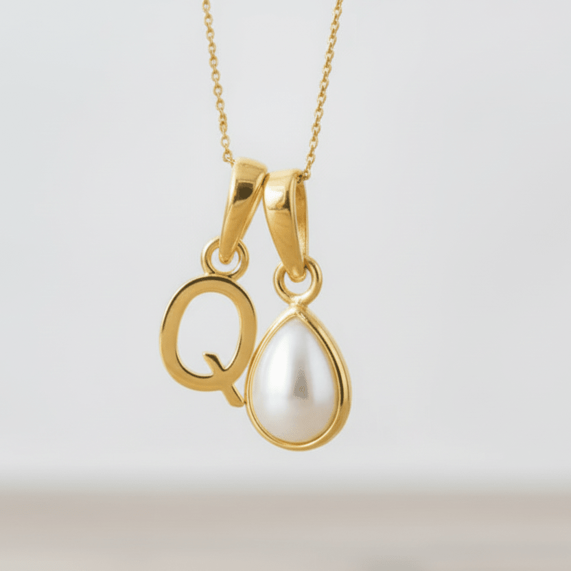 Gold initial Q pendant with a white pearl on a light gray background