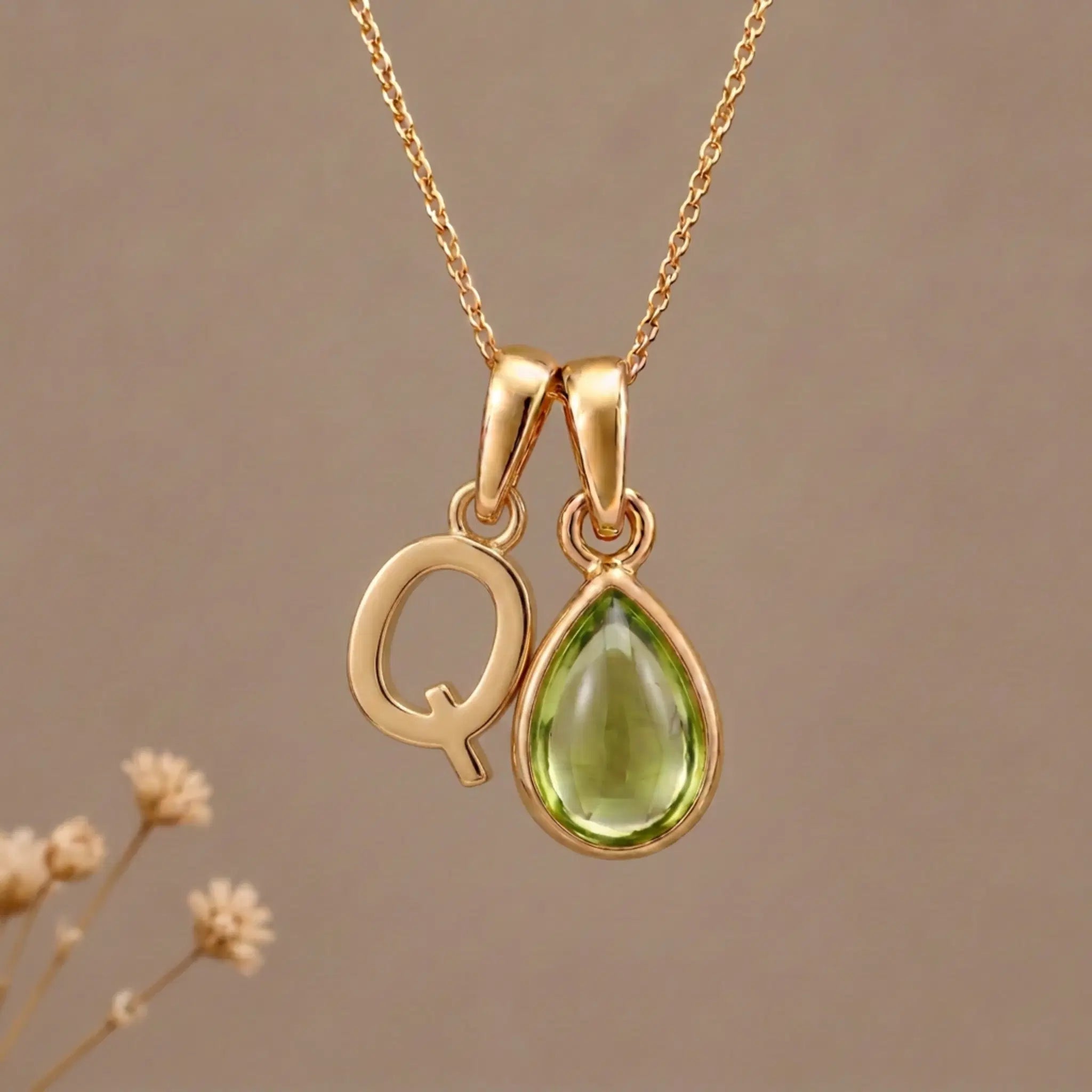 Gold Initial Q Pendant and August birthstone Natural Peridot Necklace against a warm background