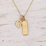 Gold Q Initial and Taurus Necklace on a fine gold chain against a light wooden background