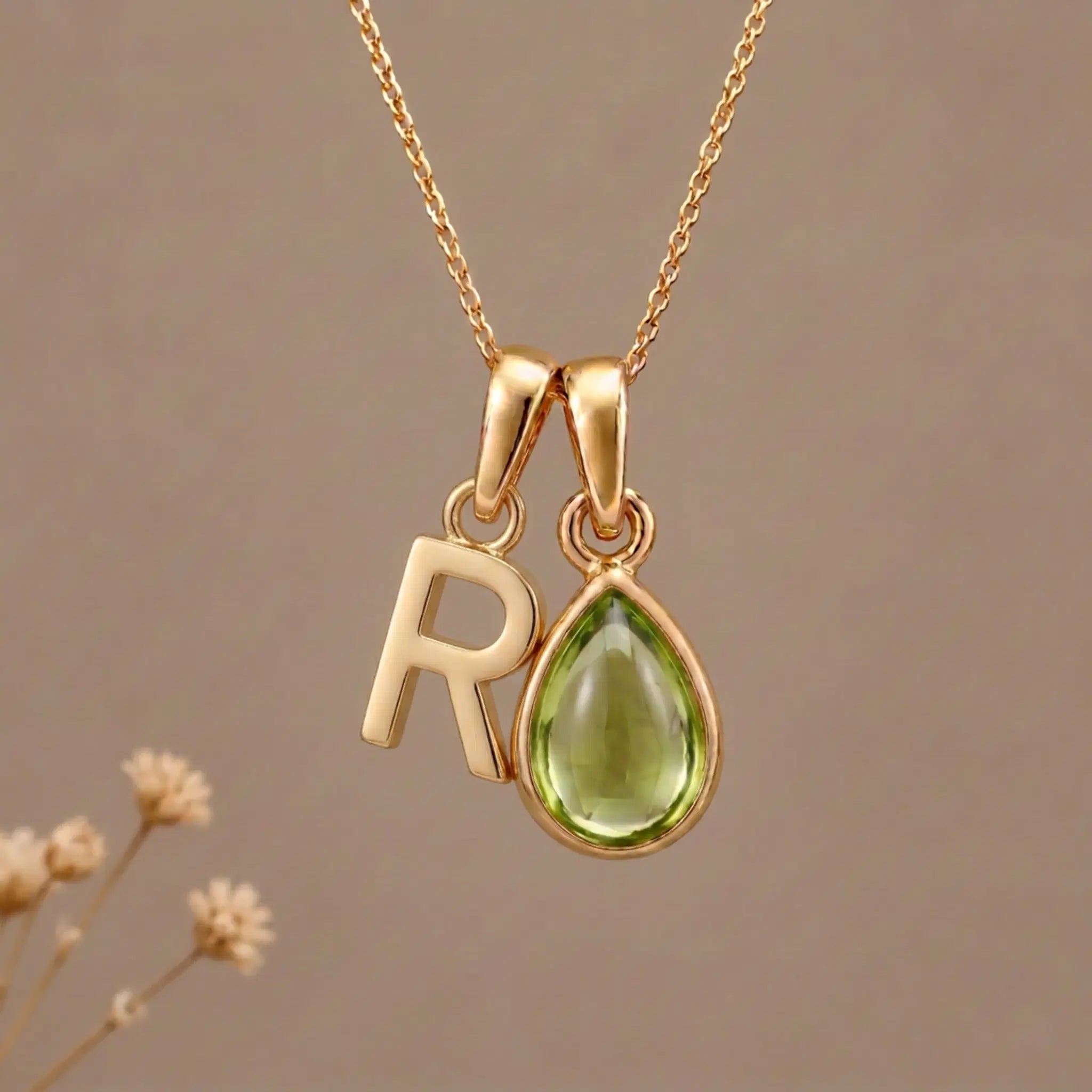 Gold Initial R Pendant and August birthstone Natural Peridot Necklace against a warm background