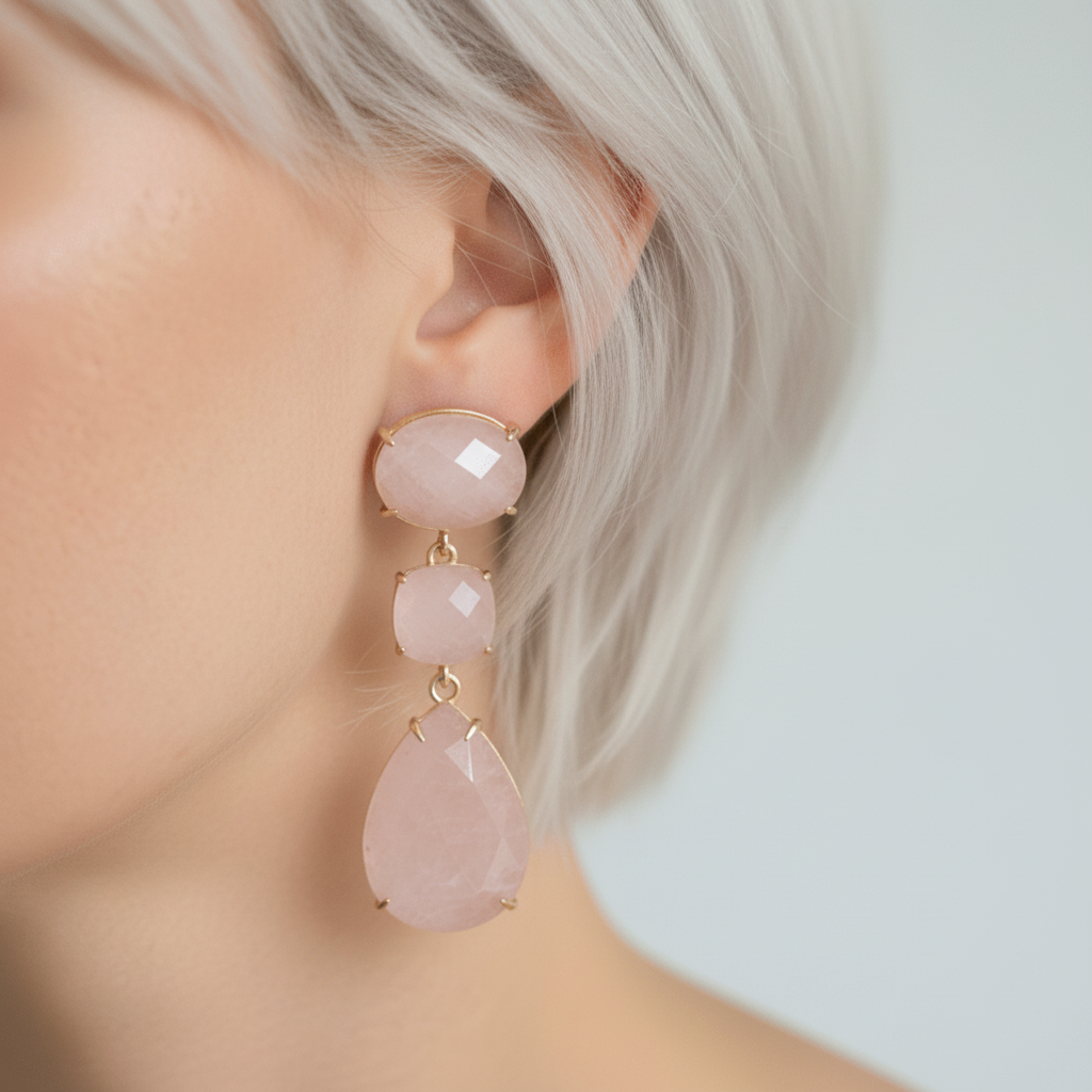 Close-up of a person wearing pink teardrop earrings with gold accents.