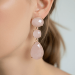 Close-up of a person wearing pink teardrop earrings with gold accents.