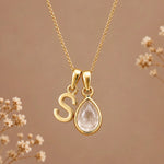 Gold initial S necklace with an April clear quartz teardrop on brown with dried flowers