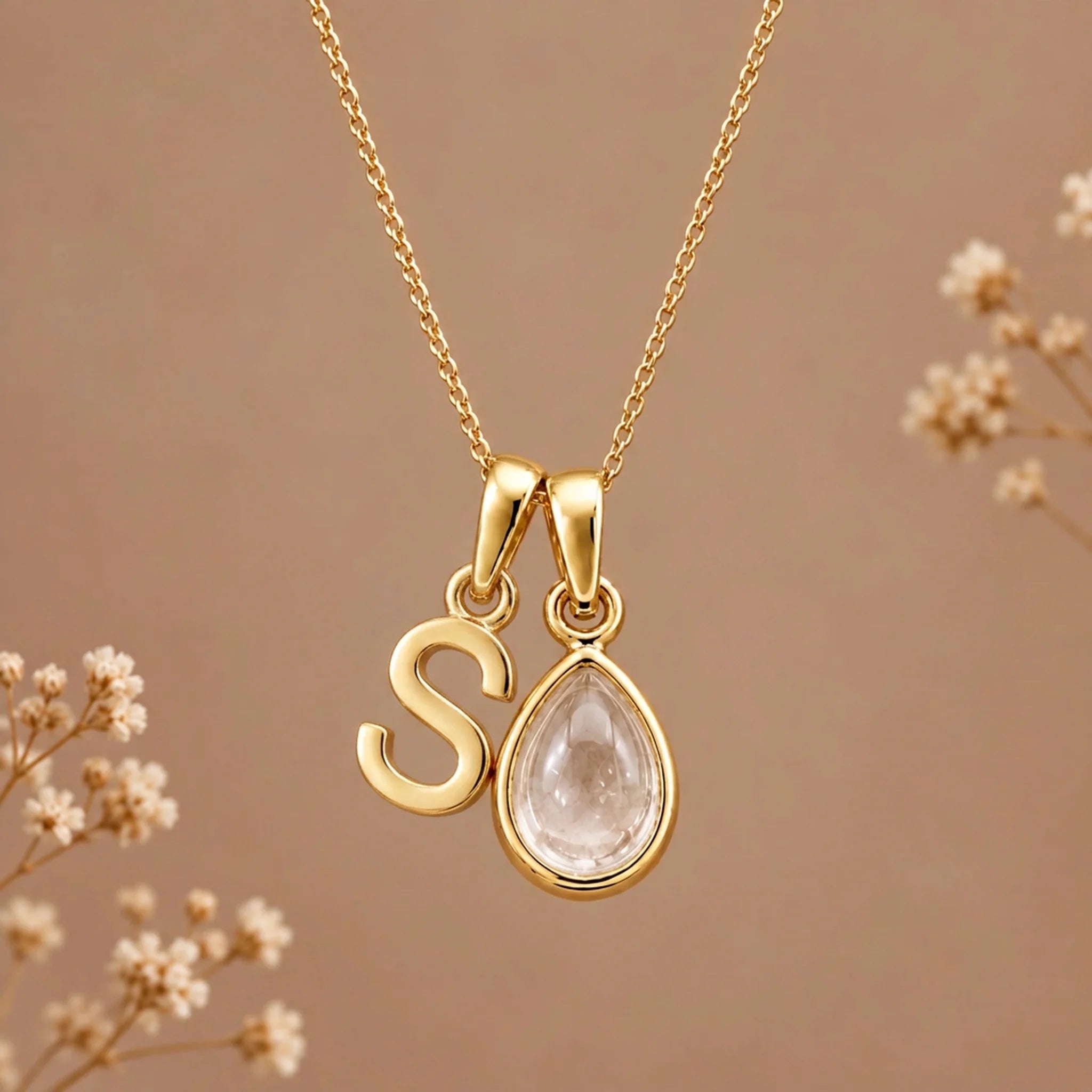 Gold initial S necklace with an April clear quartz teardrop on brown with dried flowers