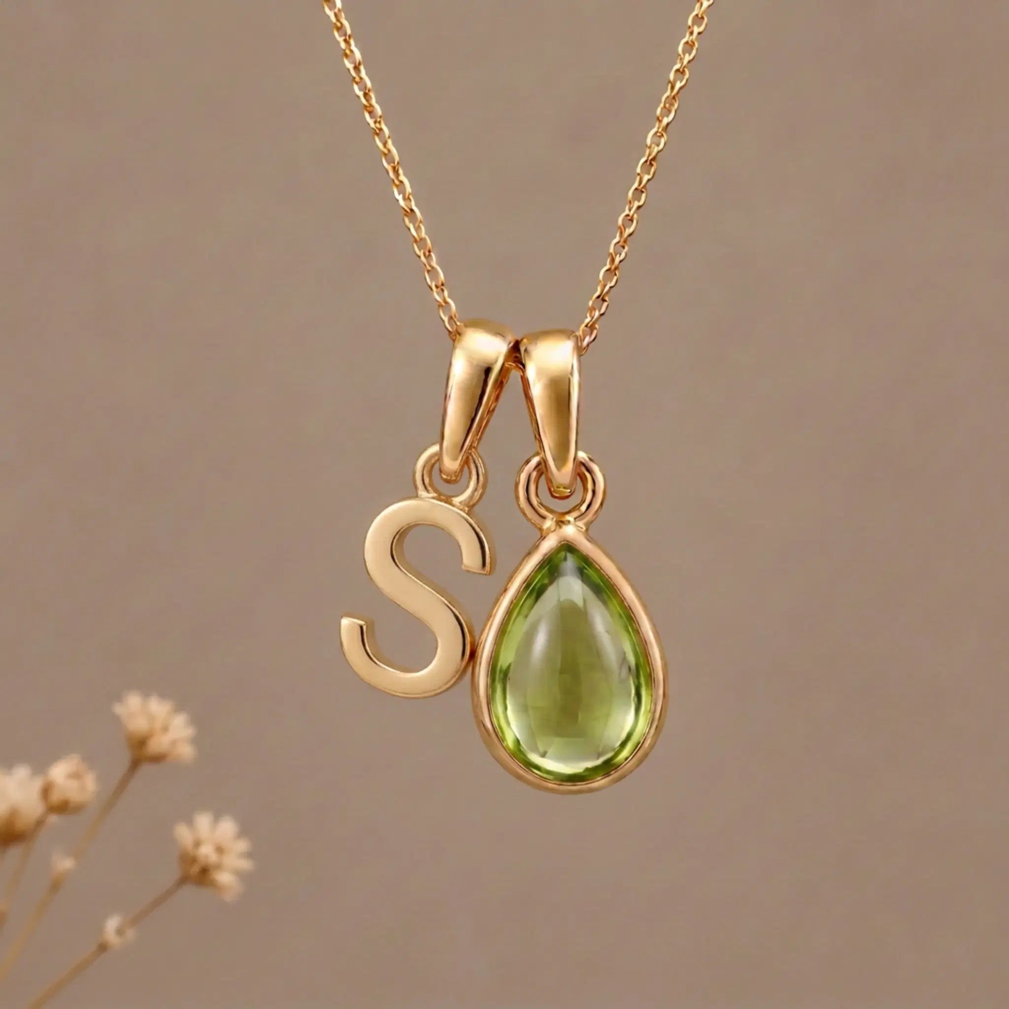 Gold Initial S Pendant and August birthstone Natural Peridot Necklace against a warm background