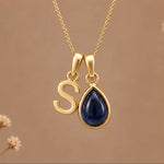 Gold Initial S Pendant and September birthstone Natural Sapphire Necklace against a warm background