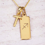 Gold Sagittarius initial necklace with a letter T charm and engraved zodiac bar on white wood, close-up