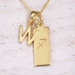 Gold Sagittarius initial necklace with a letter W charm and engraved zodiac bar on white wood, close-up