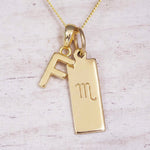 Gold Scorpio initial necklace with a letter F charm and engraved zodiac bar on white wood, close-up