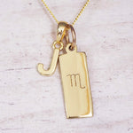 Gold Scorpio initial necklace with a letter J charm and engraved zodiac bar on white wood, close-up