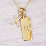 Gold Scorpio initial necklace with a letter X charm and engraved zodiac bar on white wood, close-up