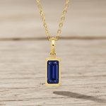 Gold necklace with a blue gemstone pendant on a white background