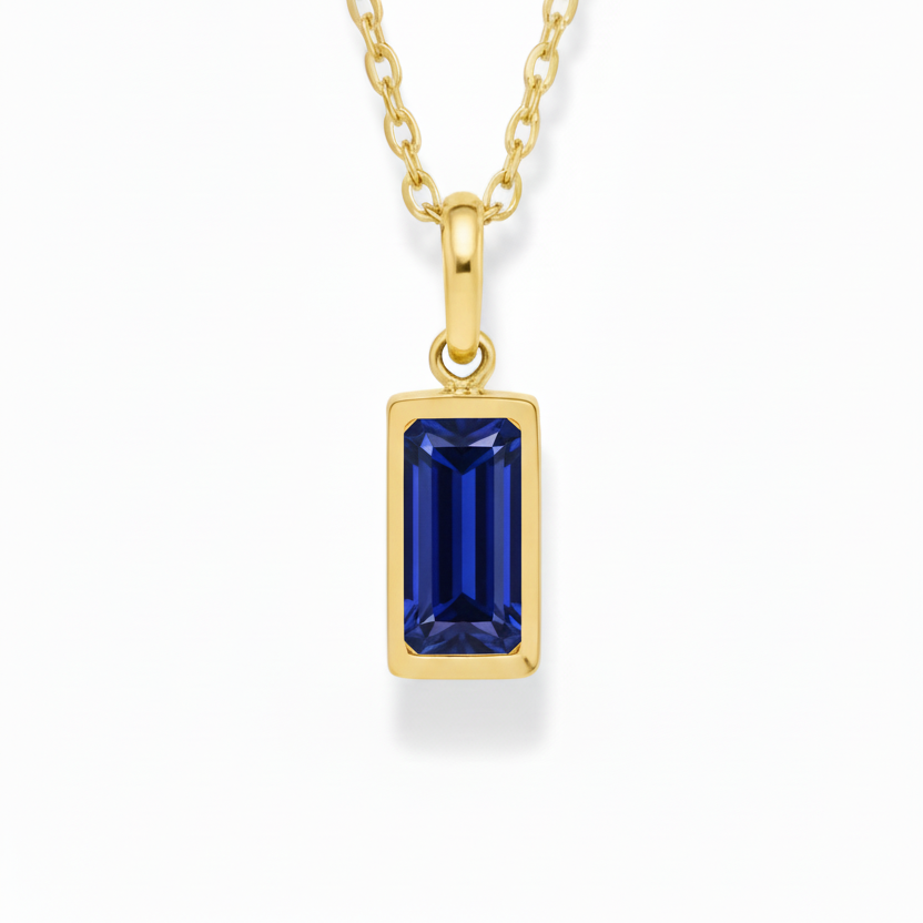Gold necklace with a blue gemstone pendant on a white background