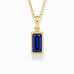 gold september birthstone necklace with blue cubic zirconia on a white background.