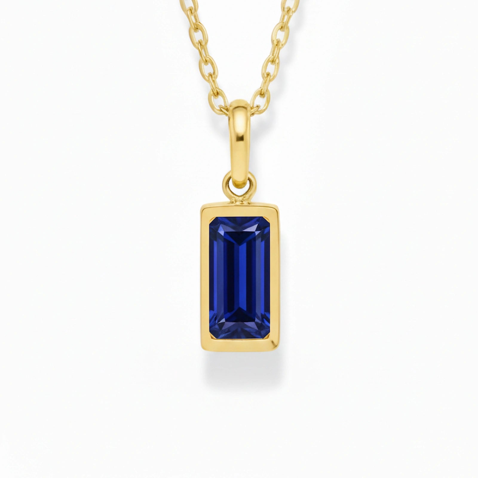 gold september birthstone necklace with blue cubic zirconia on a white background.