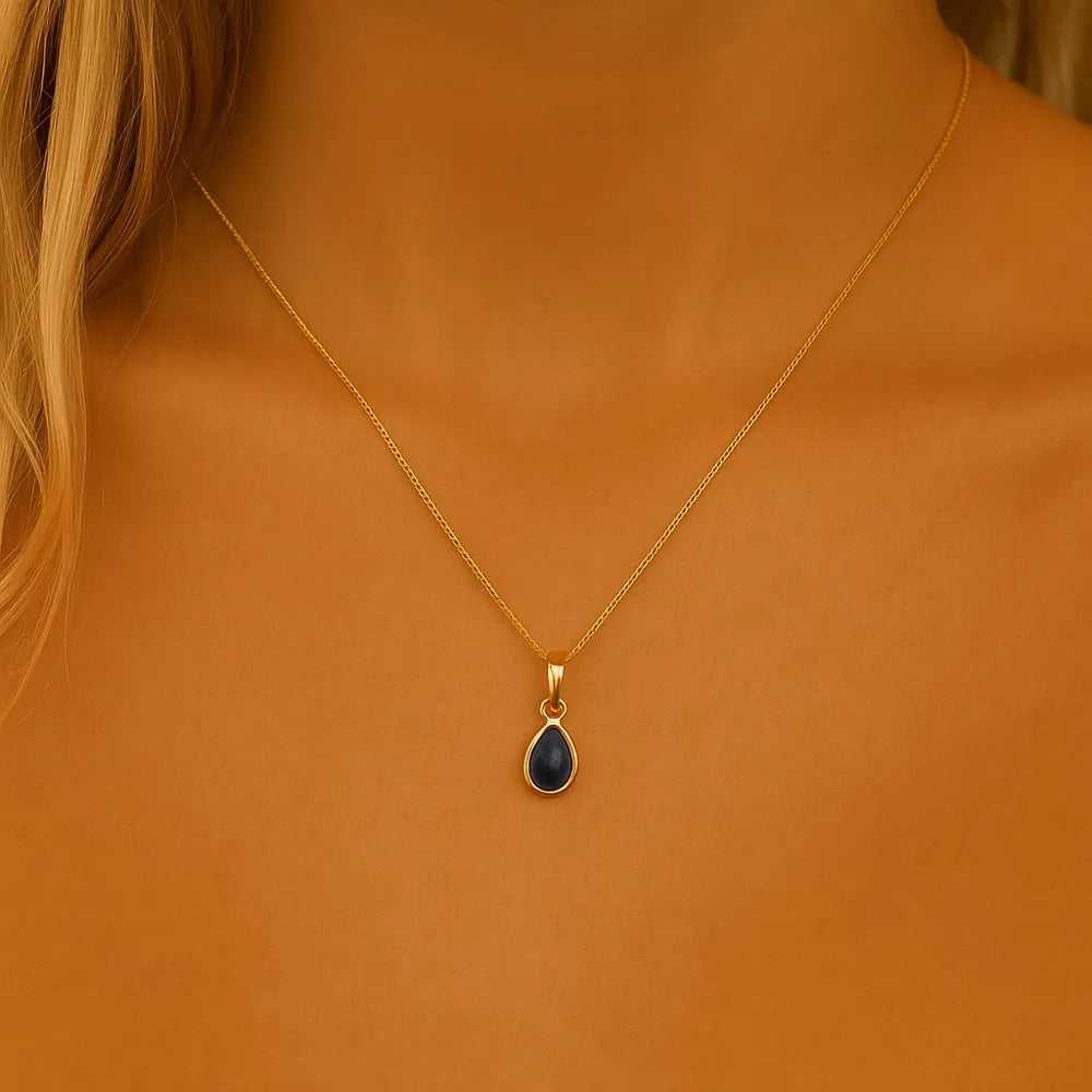 september birthstone Gold necklace with a blue sapphire pendant on a person by indie and harper australia