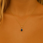 september birthstone Gold necklace with a blue sapphire pendant on a person by indie and harper australia