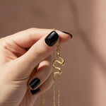 Gold serpent snake pendant necklace held