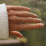 three minimalist gold stacker rings being worn on finger as a gold ring stack