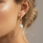 Close-up of a woman wearing a gold earring with a star-shaped pendant.