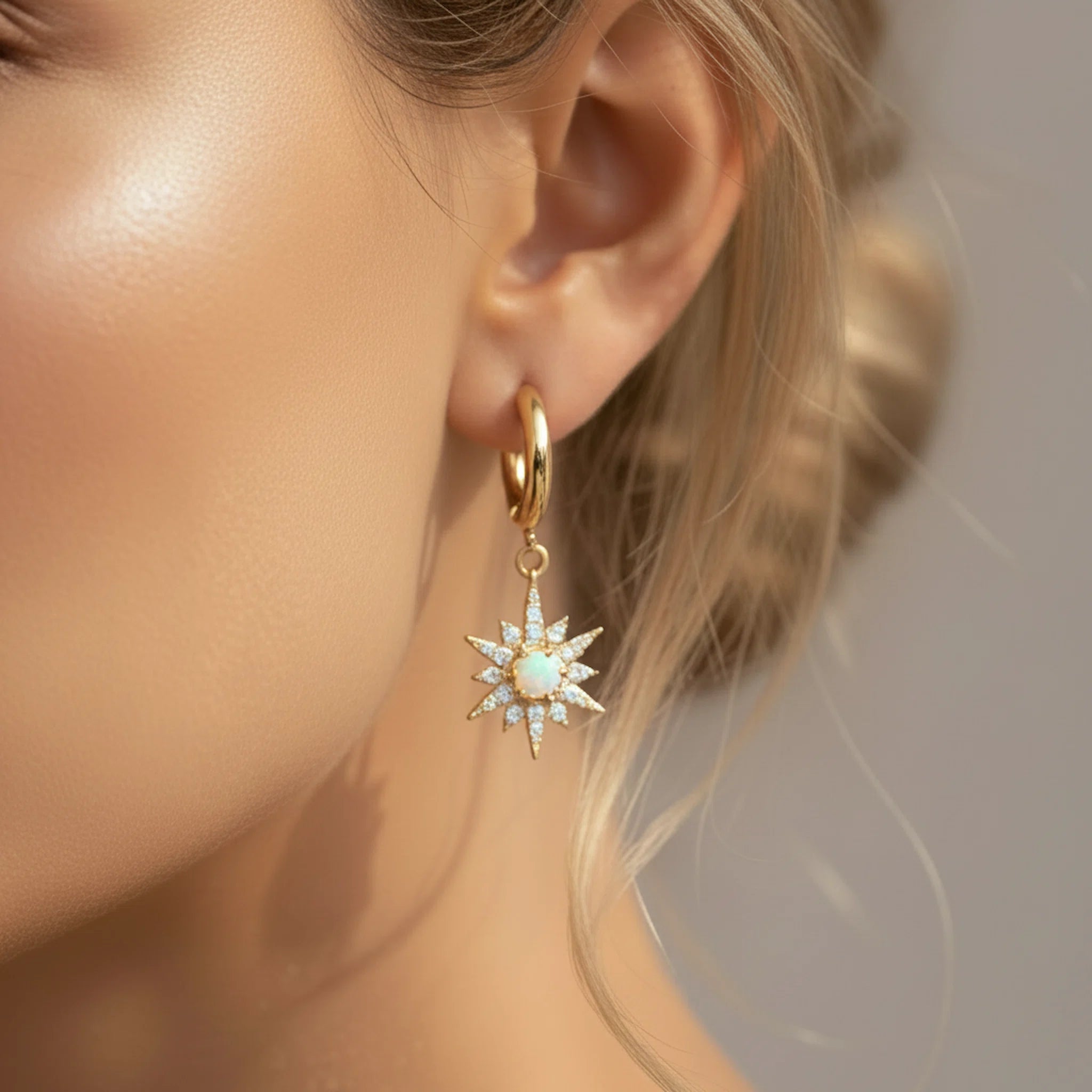 Gold hoop earring with star-shaped design worn by a person