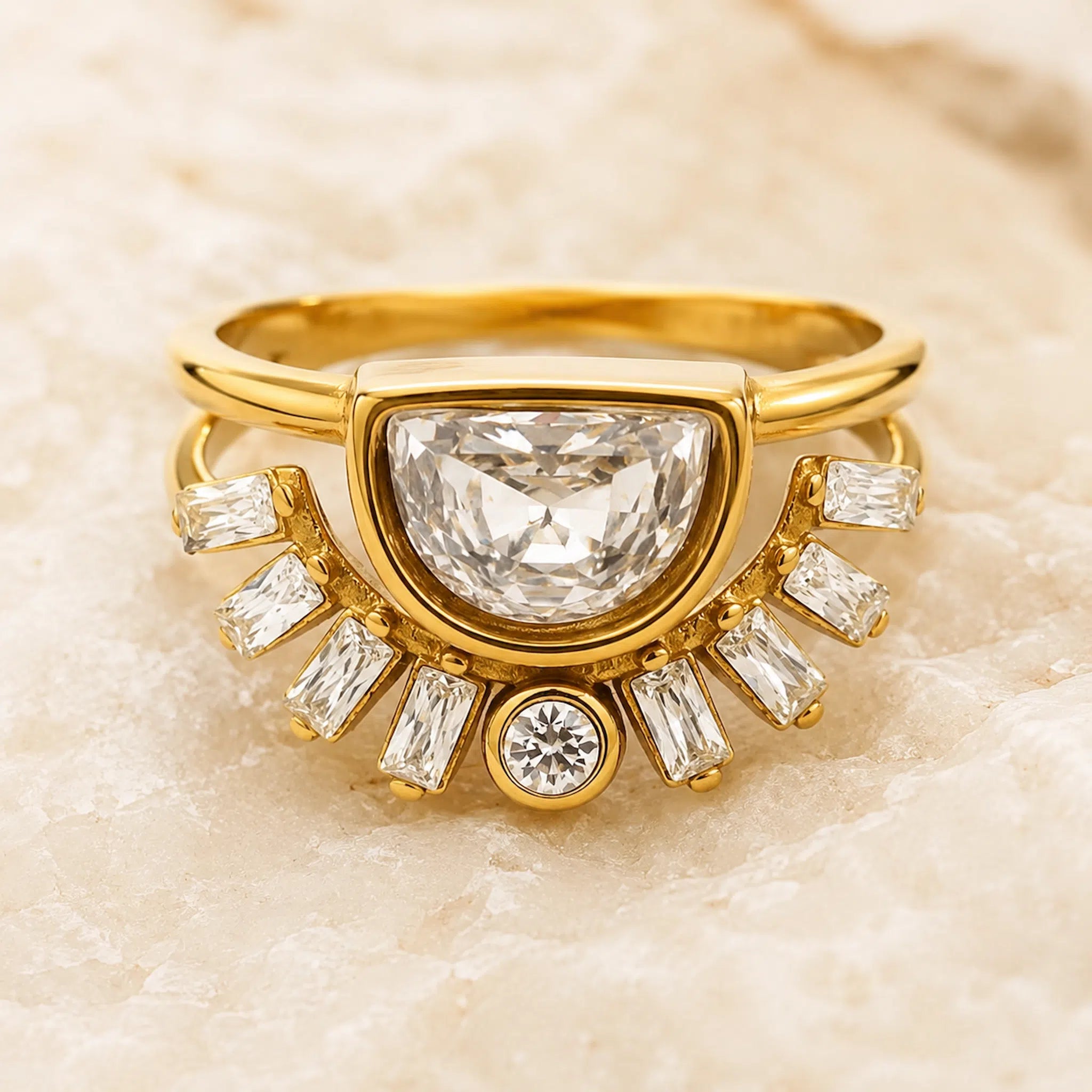 A yellow gold ring featuring a large central diamond in a semi-circular setting, surrounded by smaller baguette and round diamonds, displayed on a light beige stone background.