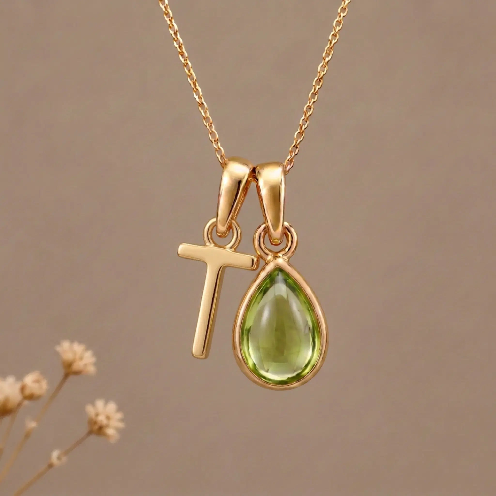 Gold Initial T Pendant and August birthstone Natural Peridot Necklace against a warm background