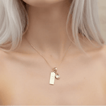 Close-up of a woman wearing a gold necklace with a taurus zodiac pendant and april birthstone pendant.