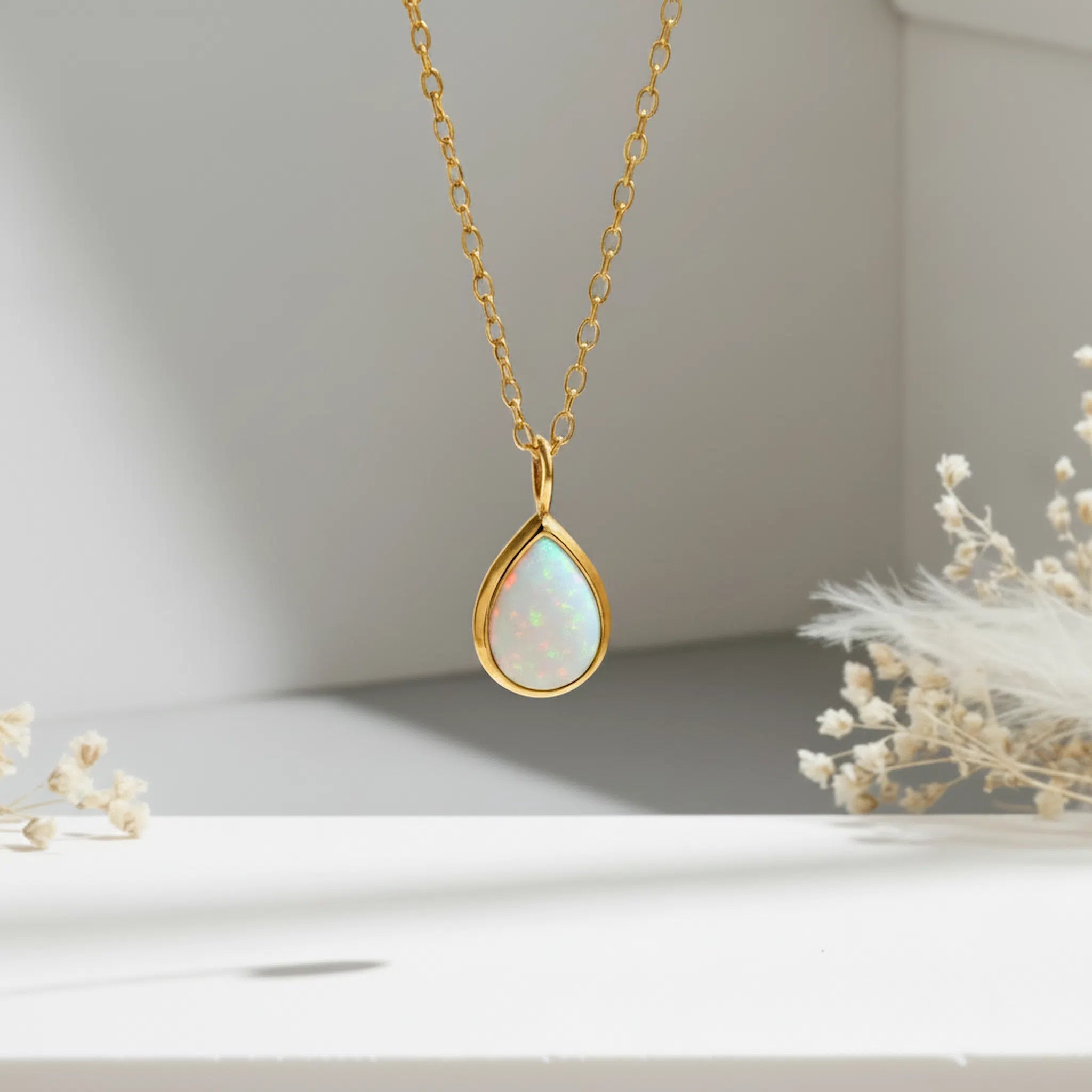 Gold white opal necklace with a teardrop-shaped opal pendant on a neutral background
