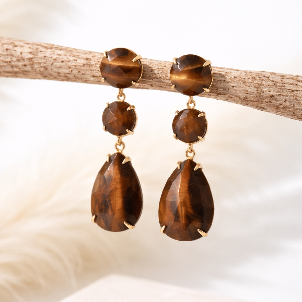 Tiger's eye teardrop earrings by Indie and Harper, on a branch with a neutral background