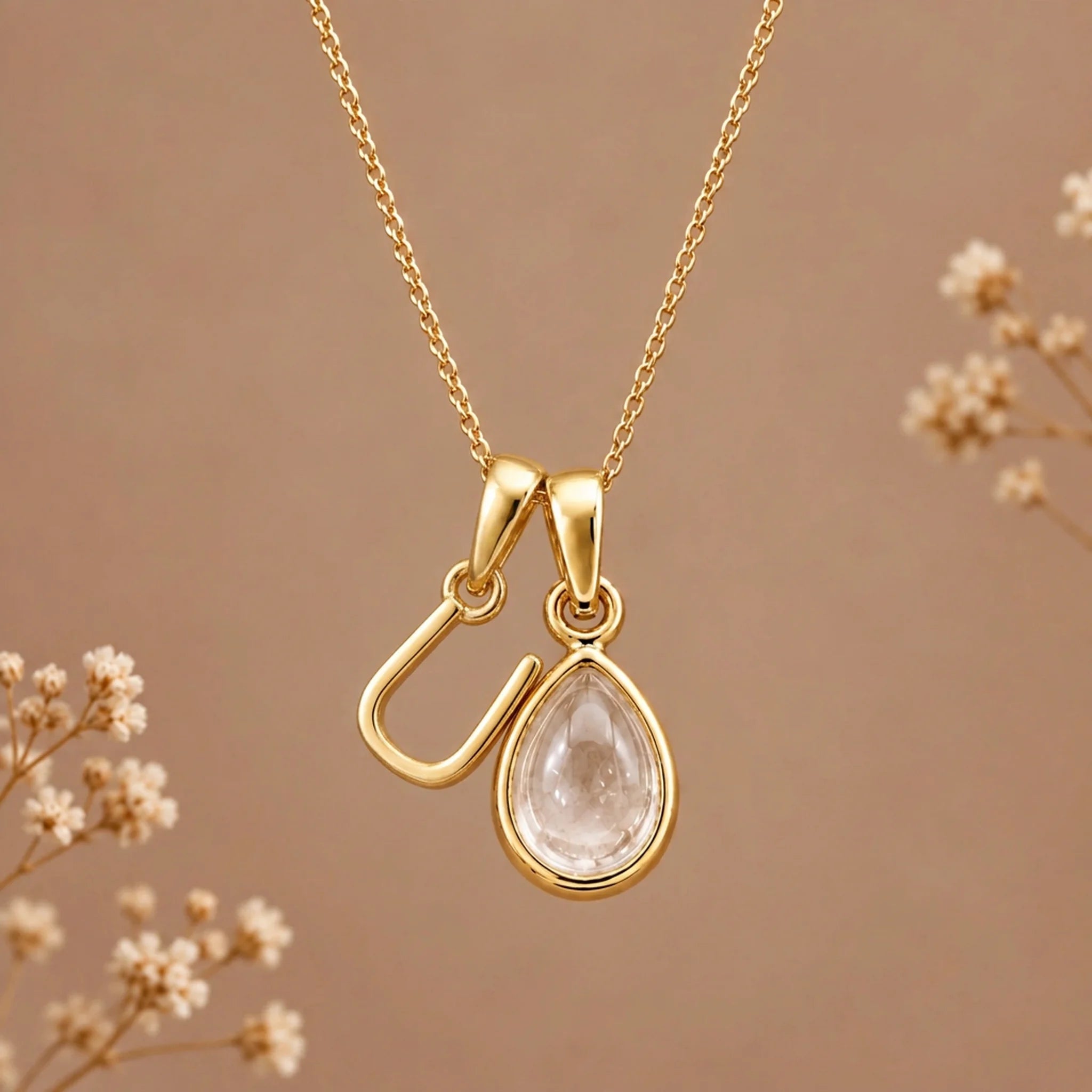 Gold initial U necklace with an April clear quartz teardrop on brown with dried flowers