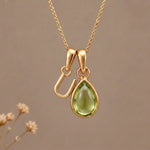 Gold Initial U Pendant and August birthstone Natural Peridot Necklace against a warm background