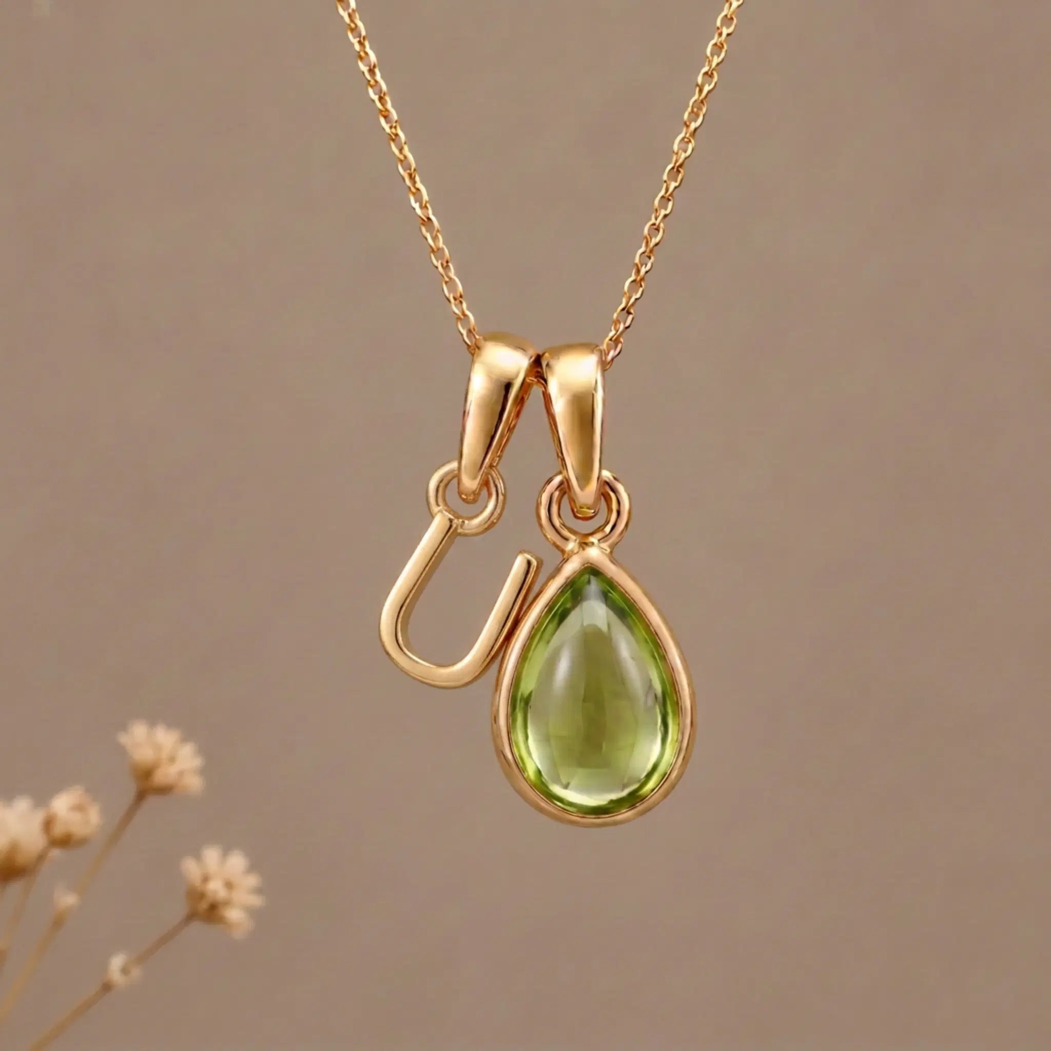 Gold Initial U Pendant and August birthstone Natural Peridot Necklace against a warm background