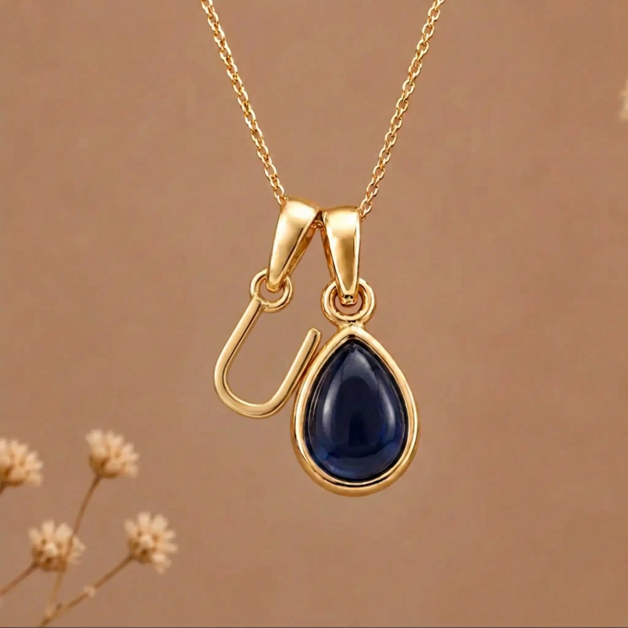Gold Initial U Pendant and September birthstone Natural Sapphire Necklace against a warm background
