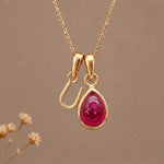 Gold Initial U Pendant and July birthstone Natural Ruby Necklace against a warm background