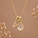 Gold initial V necklace with an April clear quartz teardrop on brown with dried flowers