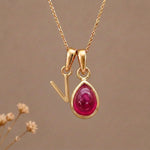 Gold Initial V Pendant and July birthstone Natural Ruby Necklace against a warm background