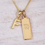 Gold Virgo initial necklace with a letter F pendant and zodiac bar on whitewashed wood