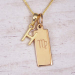 Gold Virgo initial necklace with a letter H pendant and zodiac bar on whitewashed wood