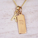Gold Virgo initial necklace with a letter K pendant and zodiac bar on whitewashed wood